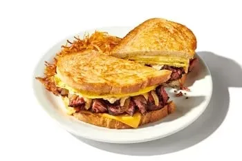 Denny’s Brisket Melt sandwich with slow-cooked brisket, cheese, and caramelized onions on toasted bread.