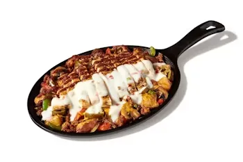 Denny’s Crazy Spicy Skillet with chicken, peppers, jalapeños, and melted cheese served hot.