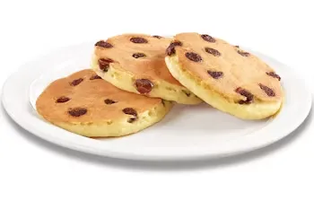 Denny’s Jr. Chocolate Chip Pancakes topped with chocolate chips, served with eggs and bacon.