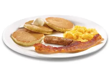 Denny’s Jr. Grand Slam kids meal with eggs, pancakes, and bacon served on a white plate.