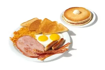 Denny’s Lumberjack Slam with pancakes, eggs, bacon, sausage, ham slice, hash browns, and toast.