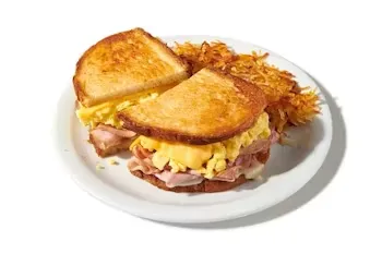Denny’s Moons Over My Hammy sandwich filled with ham, scrambled eggs, and melted cheese, served with crispy hash browns.