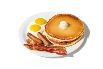 Denny’s Original Grand Slam with pancakes, eggs, bacon, and sausage links on a white plate.