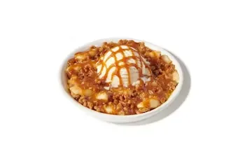 Denny’s Oven Baked Apple Caramel Pie slice topped with caramel drizzle.