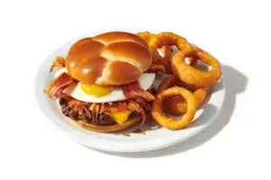 Denny’s Slam Burger with beef patty, cheese, bacon, lettuce, tomato, and crispy onion rings.