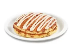 Denny’s cinnamon roll pancakes with icing drizzle.