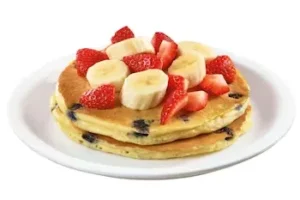 Denny’s pancakes topped with strawberries, bananas, and syrup.