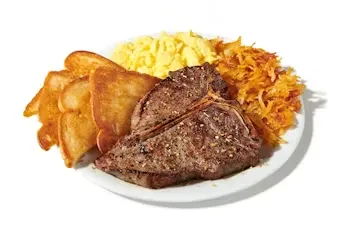Denny’s T-Bone Steak and Eggs with grilled steak, sunny-side eggs, hash browns, and buttered toast.