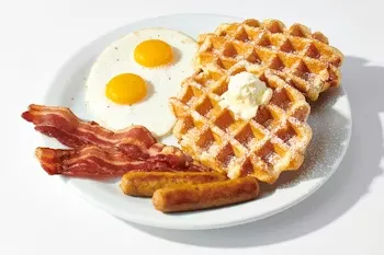 Denny’s Waffle Slam with a golden waffle, sunny-side eggs, bacon, and sausage links on a plate.